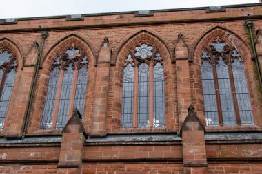 Close up exterior view of the decorative stained glass windows and red stone architecture of a 19th century church in Scotland