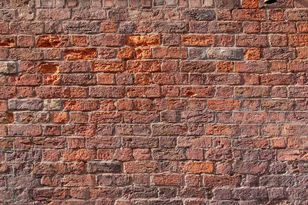 Old exterior European stone brick wall texture background in an English bond brickwork pattern, with weathered bricks in varying shades of red