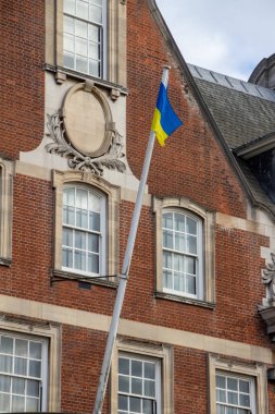 Close up view of the flag of Ukraine, waving from a beautiful old brick and stone building in England