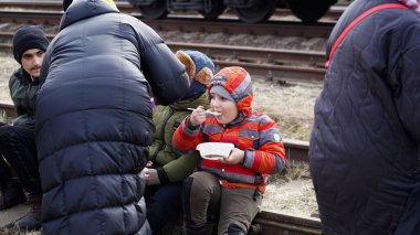 03.03.2022 Ukrayna, Ukrayna 'dan Poland.Ukraynalı mültecilerin tahliyesi sırasında kadınlar küçük çocuklarını tren raylarında otururken besledi. - Savaş. Rusya Ukrayna 'ya saldırdı