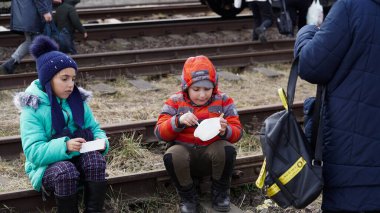 03.03.2022 Ukrayna, Ukrayna 'dan Poland.Ukraynalı mültecilerin tahliyesi sırasında kadınlar küçük çocuklarını tren raylarında otururken besledi. - Savaş. Rusya Ukrayna 'ya saldırdı