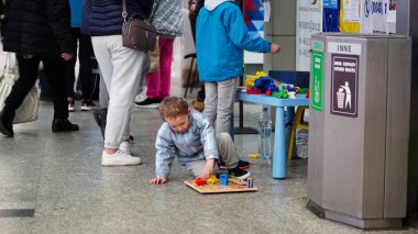 Krakow, Polonya, 26 Mart 2022 'de, küçük bir çocuk Polonya' daki yerlerinden edilen Ukraynalı çocuklar, tren istasyonunda yerde oyuncaklarla oynuyor. Rusya 'nın Ukrayna' ya karşı savaşı