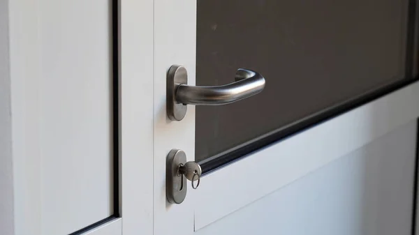 プラスチック製の白いドアの鍵穴に金属製のキーを閉じると オフィス アパートへのフロントドア モダンなインテリア フロントドアハンドル — ストック写真