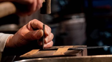 Bir demirci, Japon katana samuray kılıcının metal bir kılıcına çekiç ve küçük bir çivi kullanarak isim kazıyor.. 