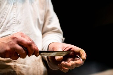 Kılıç ustası küçük katana kılıcının keskinliğini kontrol ediyor.