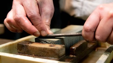 Usta bir kılıç ustası Japonya 'da bir taşın üzerinde bir bıçağı keskinleştiriyor..