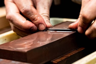 Usta bir kılıç ustası Japonya 'da bir taşın üzerinde bir bıçağı keskinleştiriyor..