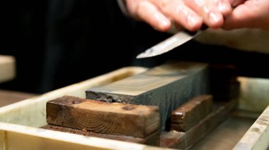 Usta bir kılıç ustası Japonya 'da bir taşın üzerinde bir bıçağı keskinleştiriyor..