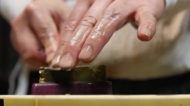 Master swordsmith is sharpening knife on grindstone with water