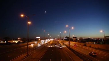 Busy traffic on a highway under the moon and blue and orange sunset sky in Toronto, Ontario, Canada. 