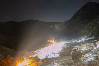 City and mountains covered by snow at night