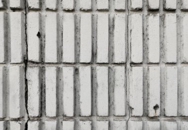 Dikey beyaz tuğla duvar yüzeyi. Çatlaklar ve lekeler var. Tasarım için boş beton duvar arkaplanı.