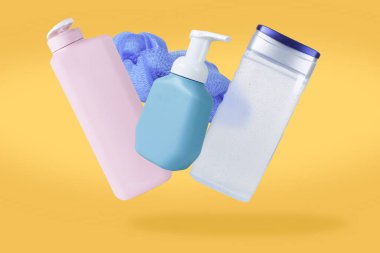 Sarı arka planda yere düşen ya da havada uçan plastik bir şişe. Vücut bakımı ürünü, şampuan, jel banyosu, sünger.