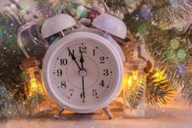 Beyaz saat gece yarısına beş dakika var. Köknar dallarının, Noel ışıklarının ve bokeh 'in arkaplanındaki saat. Noel ve Yeni Yıl kavramı.