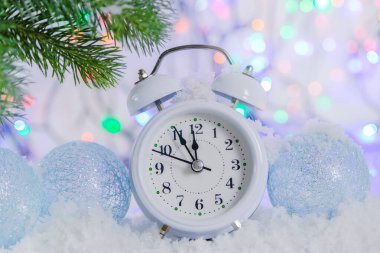 Beyaz saatlerden oluşan bir çelenk ile Bokeh 'in arka planındaki karda. 12 'ye beş var. Yakınlarda güzel mavi Noel topları var. Yeni yıl havası, giden yılın son dakikaları.