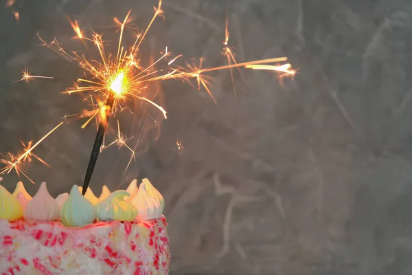 Close-up on a dark background a cake with a lit sparkler. Concept - holiday, celebration, birthday. Horizontal photo, copy space. — Stock Photo, Image