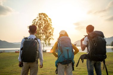 Bir grup Asyalı arkadaş sırt çantalarını toplayıp pikniğe gidiyor ve göl kenarında kamp yapıyorlar.