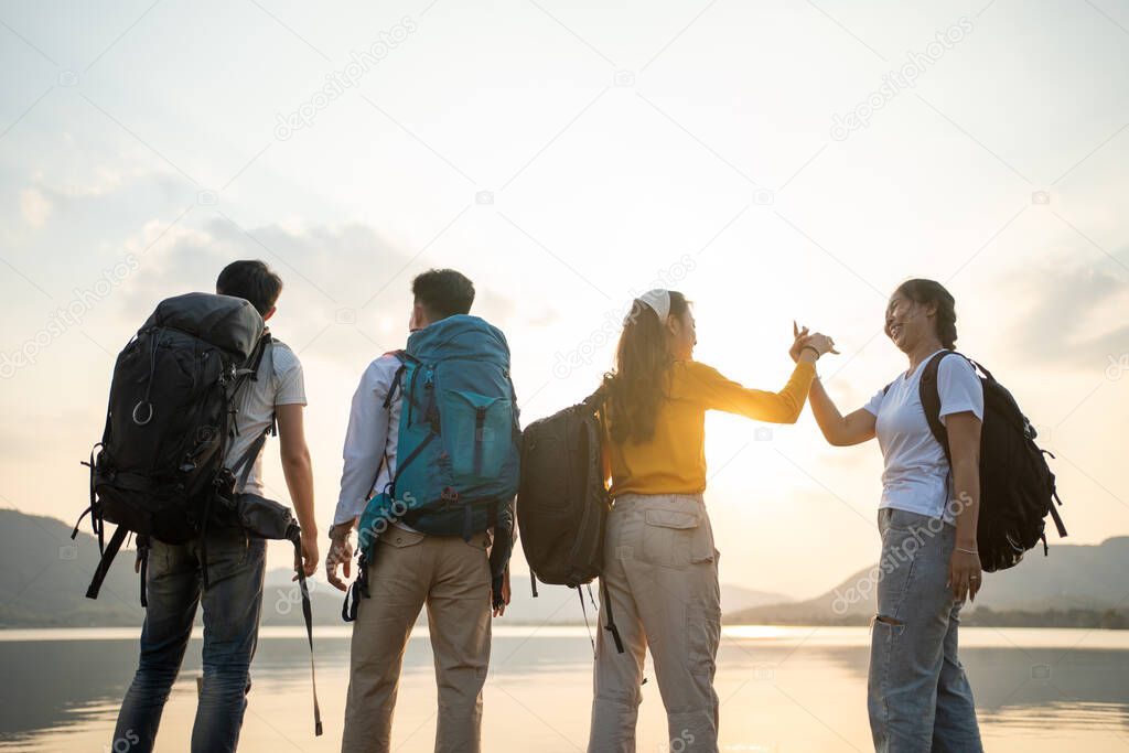 A group of Asian friends backpacking bag and walking for picnic and camping near lake