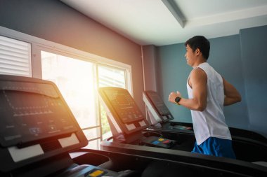 Asyalı erkekler spor salonundaki koşu bandında koşmaktan mutlu olurlar.