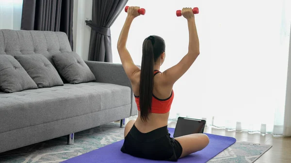 Genç Bayan Sporcu Evde Tabletle Yoga Minderinde Dambılla Egzersiz Yapıyor — Stok fotoğraf