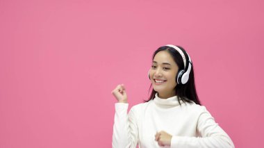 Asya 'lı kadınlar gülümsüyor ve pembe bir stüdyoda kulaklıkla müzik dinliyor.