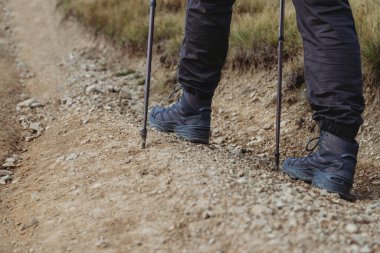 Yürüyüş sopalarıyla dağ yoluna tırmanan yürüyüşçü.