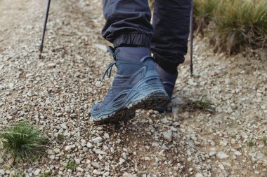 Yürüyüş sopalarıyla dağ yoluna tırmanan yürüyüşçü.