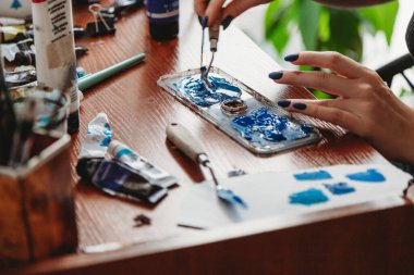 Sanat atölyesinde boya karıştıran kadın sanatçı ellerine yakın çekim