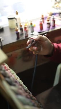 Erkeğin eli hava fırçasıyla kapanıyor, ressam akrilik boyayla boya yapıyor.