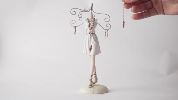 Eine Frauenhand hängt Schmuck an einen schönen Schmuckständer — Stockvideo