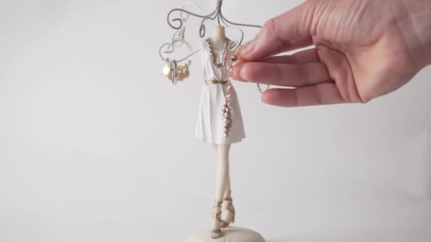 A womans hand removes rings and earrings from a beautiful jewelry stand, a close-up on a white background. — Stock Video