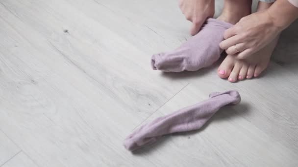 Ένα κοντινό πλάνο των γυναικών είναι τα πόδια, η γυναίκα βάζει ροζ κάλτσες στα πόδια της — Αρχείο Βίντεο