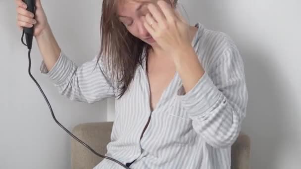Une femme brune sèche les cheveux mouillés avec un sèche-cheveux à la maison — Video