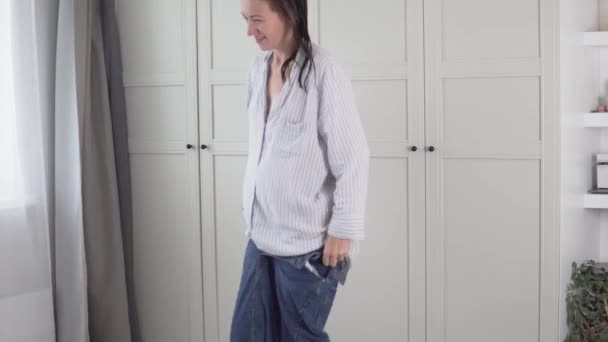 Жінка в нічній сорочці вранці одягає джинсову спідницю — стокове відео