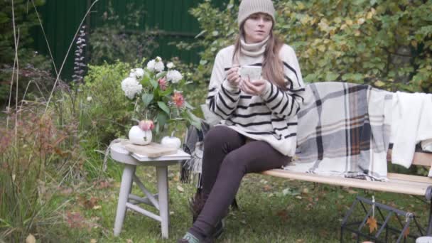 Una hermosa mujer de moda bebe té en el parque con su perro Jack Russell Terrier en el otoño — Vídeos de Stock