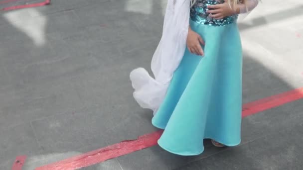 A funny little girl stands in line in a long elegant dress with sequins — Stock Video