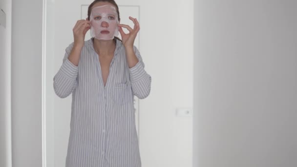 Een vrouw huisvrouw draagt een stof masker thuis — Stockvideo