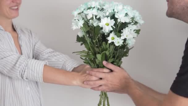 Женщина дарит мужчине букет белых хризантем, мужчина вручает букет женщине — стоковое видео