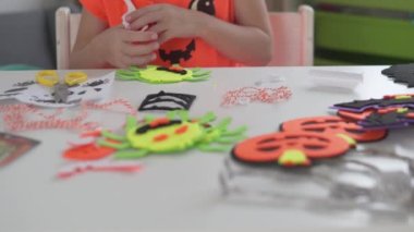 Yakın plan, çocuk Cadılar Bayramı 'nda evi dekore etmek için kağıttan örümcekler yapıyor.