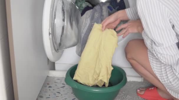 Una mujer desmonta la lavadora después del lavado, saca las cosas lavadas — Vídeo de stock