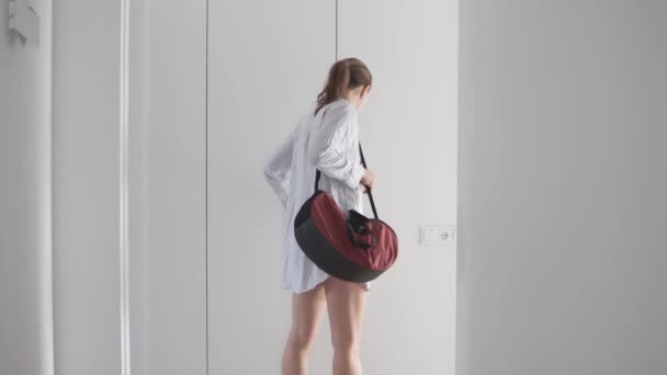 Žena nosí tašku se sportovní uniformou v prádelně. — Stock video
