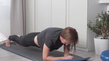 Bir kadın evde spor yapmaya çalışıyor.,