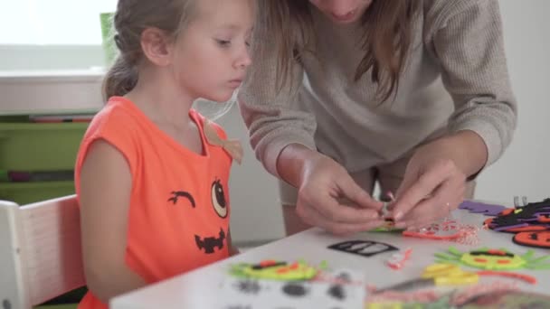 女の子と彼女の母親はハロウィンのお祝いのために装飾をします — ストック動画