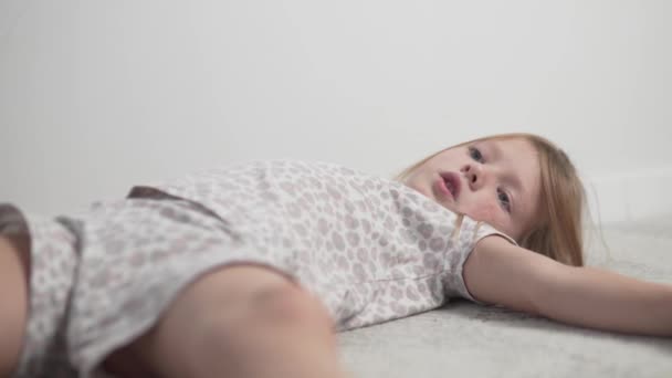 Primer plano, triste niña molesta en pijama yace en el suelo en la habitación — Vídeos de Stock