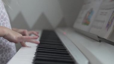 Yakın plan, beyaz bir elektronik piyanonun anahtarının üzerinde bir çocuk eli.