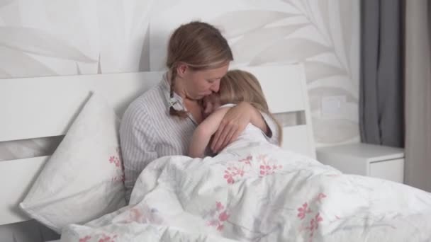 Милая счастливая мама с маленькой дочерью в постели по утрам — стоковое видео