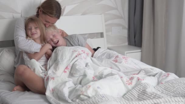Mamma kramar sina barn i sängen på morgonen — Stockvideo