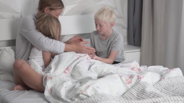 Мама грається з дітьми вранці в ліжку з сином і дочкою. — стокове відео
