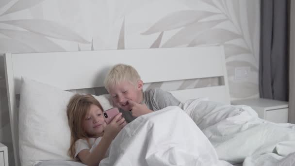 Дети играют с мобильного телефона в постели по утрам. — стоковое видео