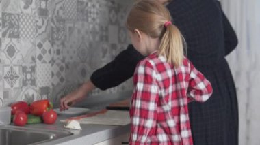 Kızım ve annem mutfakta birlikte yemek pişiriyorlar.